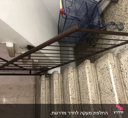 מעקה מתכת חום ליד מדרגות אבן